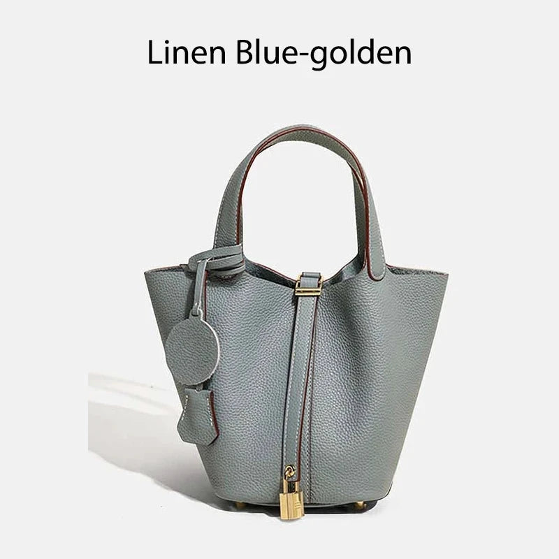 Sac à main seau Mendy en cuir véritable, Linen Blue-golden bleu gris, poignées courtes et fermoir doré.